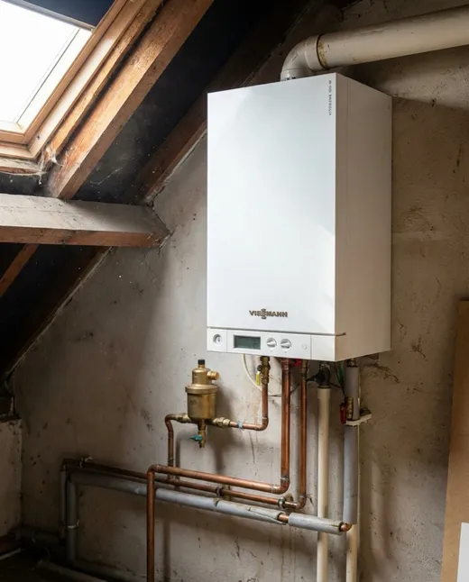 Witte Viessmann Vitodens gasketel onder een schuin dak met houten balken en nieuw leidingwerk