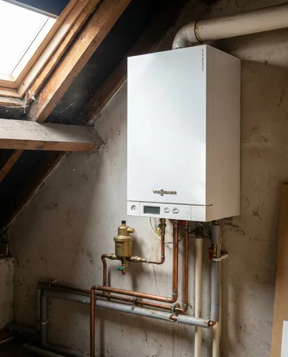 Witte Viessmann Vitodens gasketel onder een schuin dak met houten balken en nieuw leidingwerk